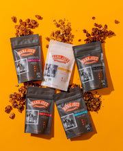 Load image into Gallery viewer, Nana Joes Granola starter pack, bags laid down and spilled on bright orange background

